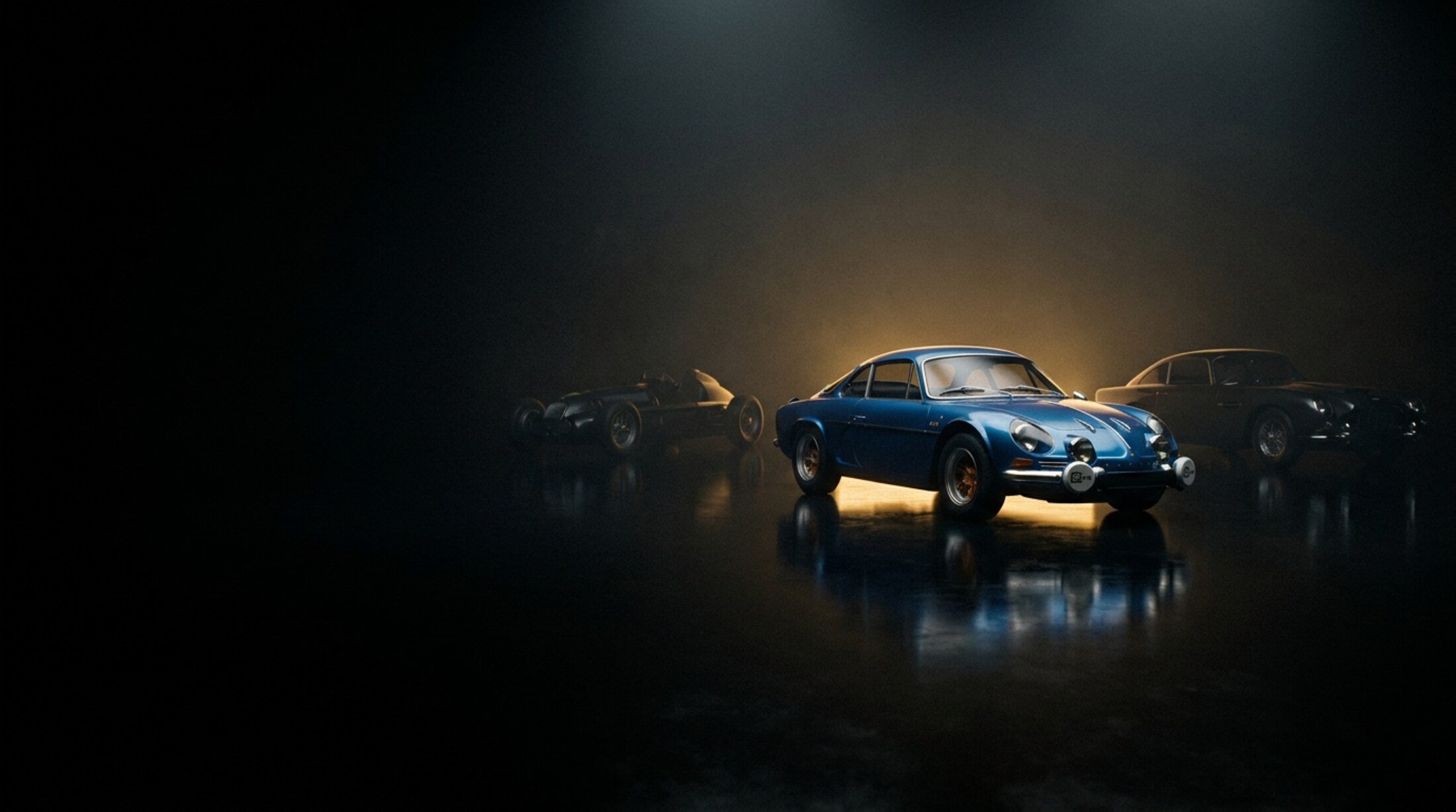 Trois voitures de collection en studio sombre, halo doré et sol réfléchissant : au centre une Alpine A110 bleue, une monoplace de course à gauche, une GT ancienne à droite